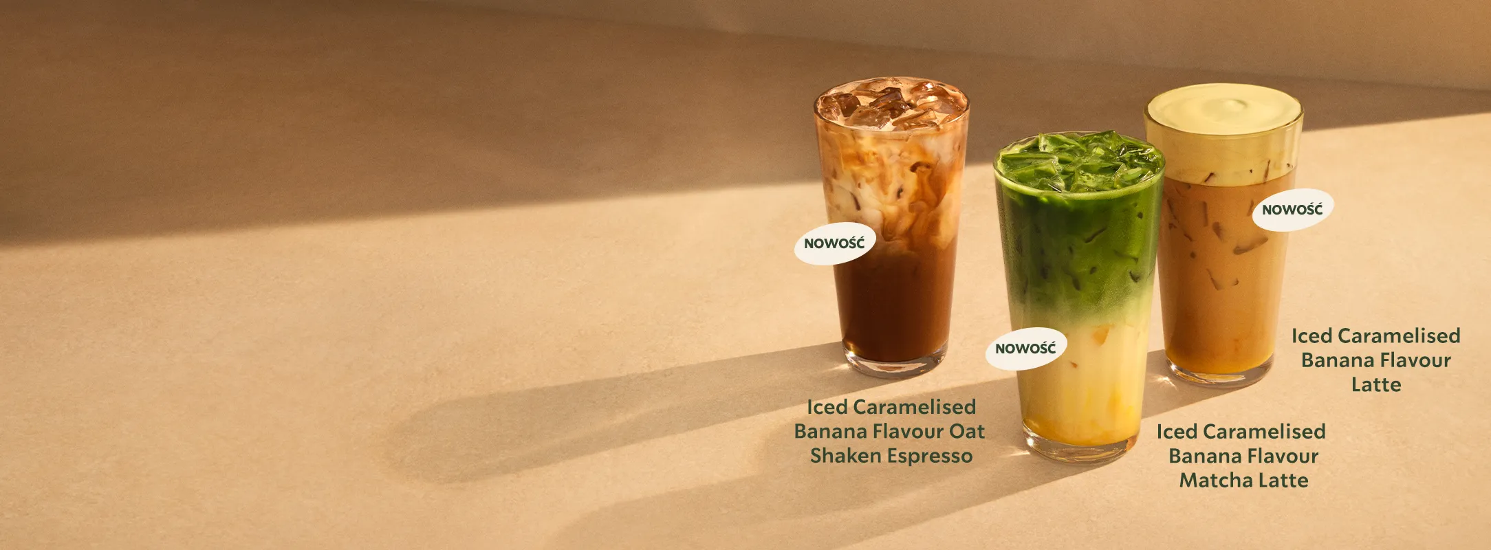 Trzy mrożone kawy z karmelizowanym bananem: oat shaken espresso, matcha latte i latte, ustawione na jasnym tle.