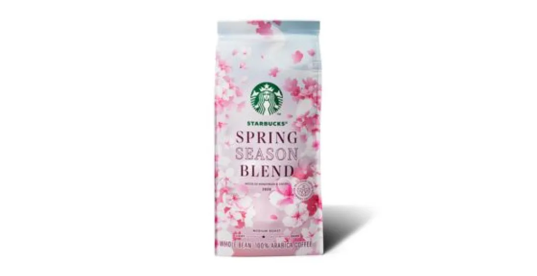 Opakowanie kawy ziarnistej Starbucks Spring Season Blend ozdobione różowymi kwiatami wiśni na białym tle. Na froncie widoczne jest zielone logo Starbucks oraz napis ‘Spring Season Blend’. Opakowanie stoi na białym tle z lekkim cieniem.